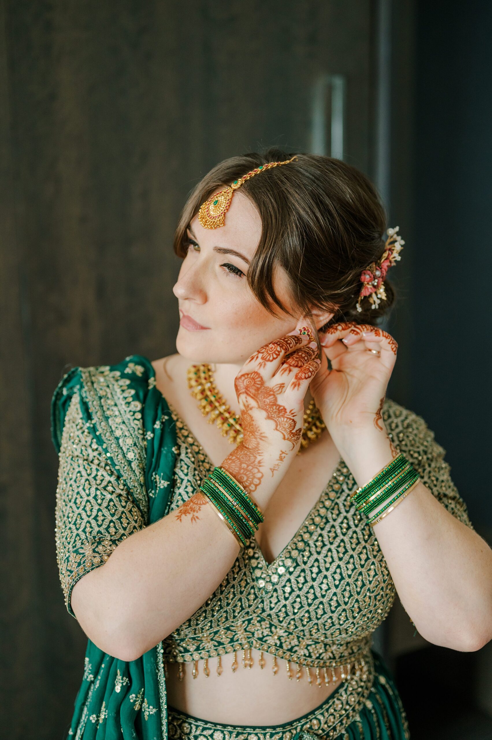 Detail shot of bride putting on earrings for Indian Wedding